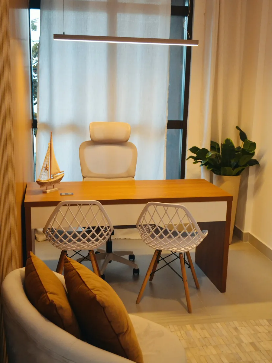 Bureau terminé : murs clairs, plan de travail en bois et fauteuils