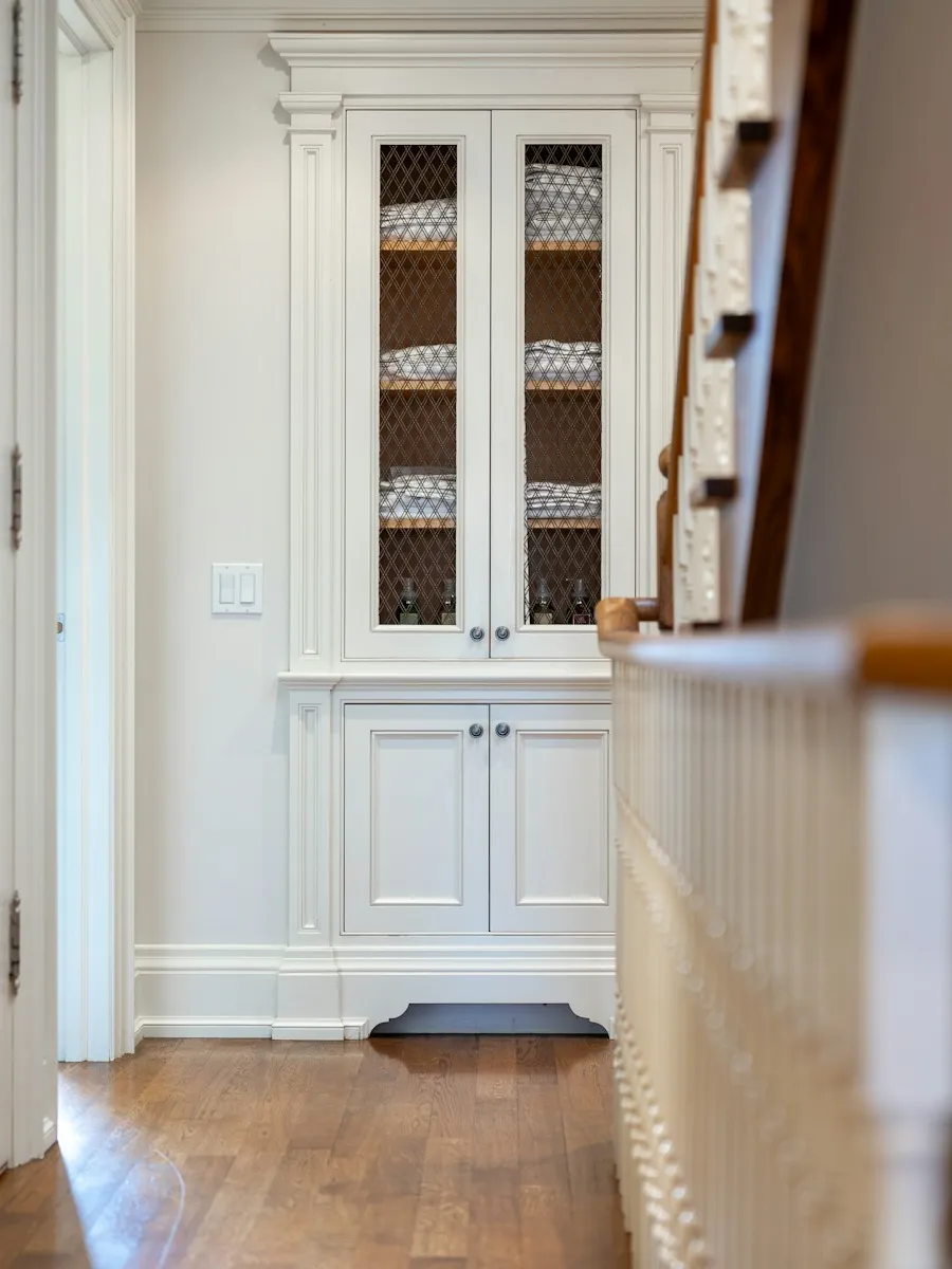 Entrée avec placard blanc et départ d'escalier en bois