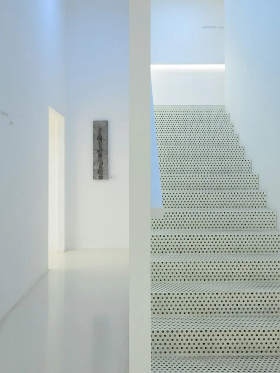 Montée d'escalier entièrement blanche, marches et mur d'un seul ton